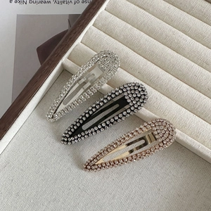 Close-up of sparkling rhinestone oval hair clips in silver, black and rose gold finishes