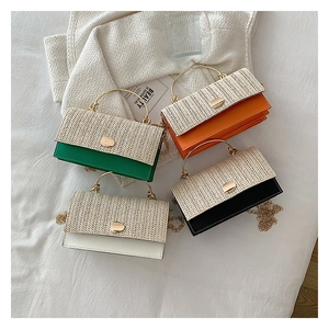 Detail of woven straw handbags in green, orange, black, and white with metal handles