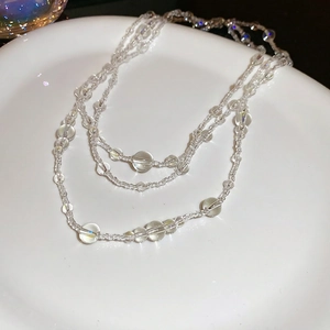 Elegant multi-layered glass bead necklace displayed on a white ceramic plate