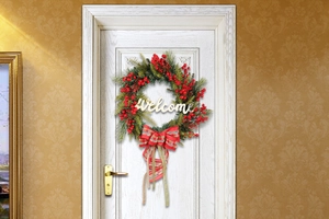 Detail of Christmas wreath with red berries, pine needles, and a Welcome sign on a white door