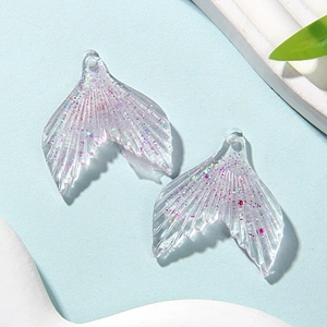 Close-up of glittery resin mermaid tail charms for DIY jewelry making with shell decor