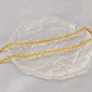 Macro shot of gold titanium steel link chain on textured glass plate detail