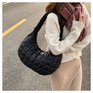 Street style shot of a black quilted puffer bag showing its texture on a city street