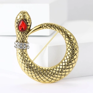 Exquisite gold snake brooch with a red crystal head and rhinestone details on white background