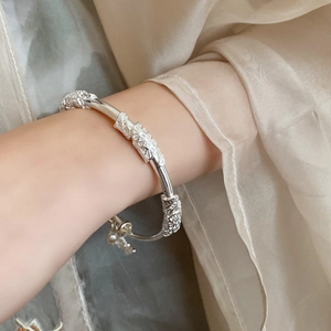 Detail of silver lotus bamboo open bracelet with vintage floral relief and small charm