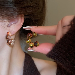 Detailed close-up of retro C-shaped earrings with leopard print amber resin beads