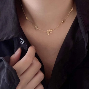 Detailed close-up of a 925 silver golden necklace with bird and flower charms on a model