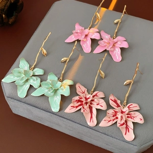 Three pairs of vintage orchid earrings in pink and mint green enamel on velvet tray