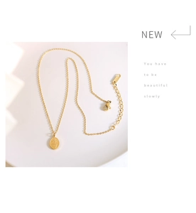 Detail of gold leaf pendant necklace with adjustable lobster clasp on white plate