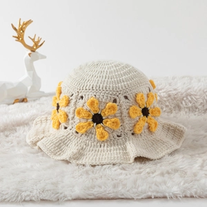 Detail of hand-woven crochet bucket hat featuring a yellow sunflower on beige knit