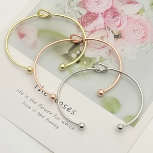 Detailed close-up of three metallic knot bangles in gold silver and rose gold finishes