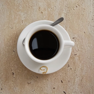 Close-up of golden sunburst zircon ring elegantly perched on a white coffee cup saucer