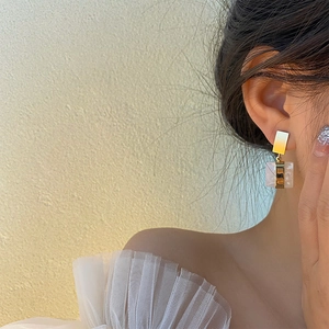 Boucles d'oreilles géométriques carrées en métal doré et texture marbre portées par mannequin
