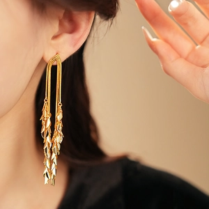 Close-up of gold leaf tassel earrings with sleek snake chains on a female model