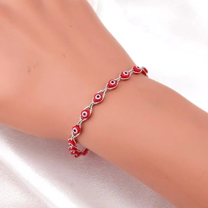 Evil eye anklet with red beads and silver chain on a white silk background