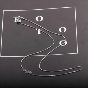 Detailed view of silver box chain necklace with a secure spring clasp on black card