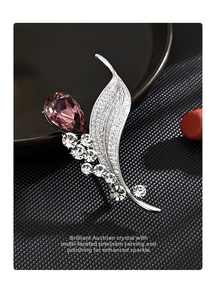 Detailed shot of leaf brooch with purple crystal and silver-tone metal on black background