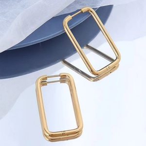 Polished gold stainless steel large rectangular earrings on a elegant mirror surface