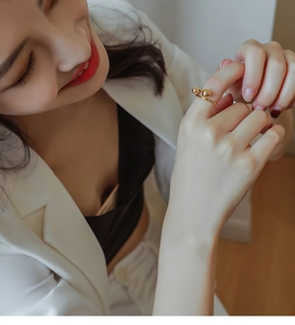 Detail of a minimalist gold open ring with dual metal beads worn on a finger