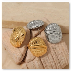 Detail of oval striped button stud earrings in gold and silver on stone base