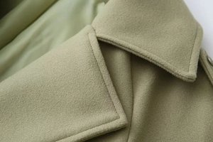 Macro detail of olive green wool coat texture with fine stitching and collar craftsmanship