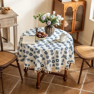 Detailed view of blue floral cotton linen tablecloth with delicate tassel edges on a table