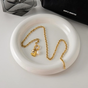 Close-up of golden pearl necklace with heart charm and zircon pendant on a tray
