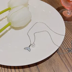 Elegant silver mermaid tail pearl necklace on white ceramic tray with tulips