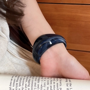 Deep blue marble acrylic chunky open bangle shown on wrist in elegant lifestyle setting