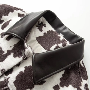Detail of cow print faux fur jacket showing high-quality leather collar and metal button
