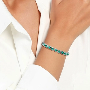 Detailed view of tennis bracelet featuring heart-shaped emerald green zircons and silver base
