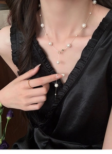 Close-up of elegant Y-shaped pearl necklace and minimalist rose gold ring on model