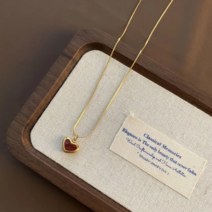 Detailed shot of a vintage gold heart necklace on a premium walnut jewelry display tray