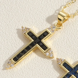 Macro shot of 14K gold plated cross pendant with black gemstone and white zircons