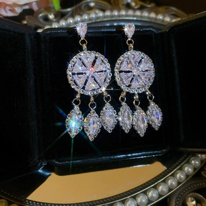 Gros plan sur des boucles d'oreilles à pompons en argent et zircons sur socle en velours