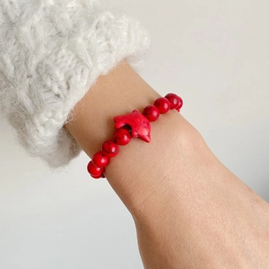 Detail of red turquoise stone beaded bracelet featuring a dolphin pendant on a wrist