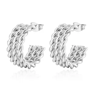 Macro shot of silver C-shaped twisted rope earrings with intricate woven metal texture