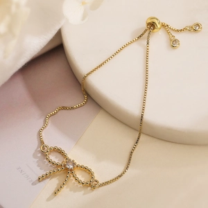 Elegant gold bow charm bracelet with zircon accent and adjustable sliding clasp