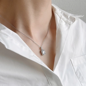 Detailed close-up of a square zircon pendant on a silver chain worn by a model