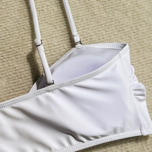 Dettaglio delle spalline regolabili e fibbie in metallo sul top bikini bianco lavorato