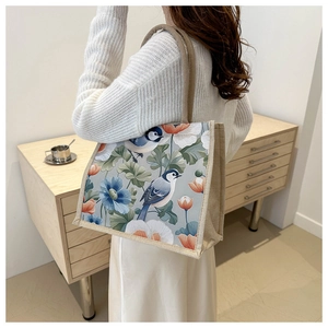 Detail of linen tote bag featuring vibrant flower and bird print with woven handles