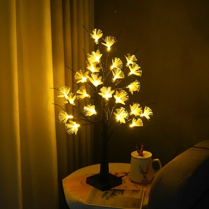 Detail of warm yellow fiber optic flowers on a birch tree lamp with a black base