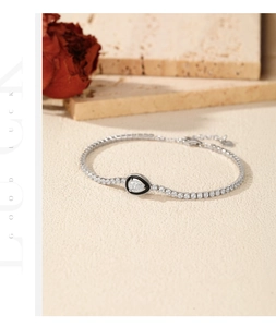 Macro shot of silver tennis bracelet with pear-shaped black enamel water drop pendant