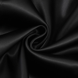 Detail shot of black satin dress fabric showing glossy texture and elegant ruffles