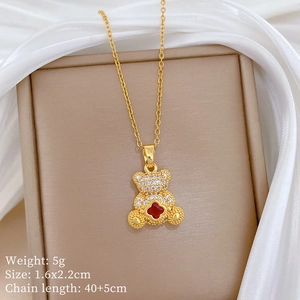 Close-up of gold bear necklace with red clover gemstone pendant in a jewelry box