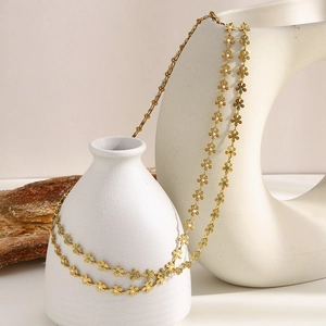 Detail of bohemian 18K gold plated necklace with white and turquoise enamel flowers