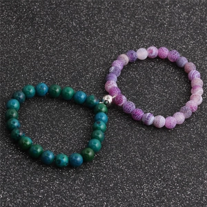 8mm couple stone beads bracelets with magnetic heart charm on a black textured surface