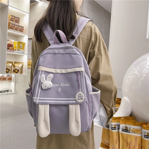 Cute purple nylon backpack with white rabbit ears and embroidery shown from a side-back view