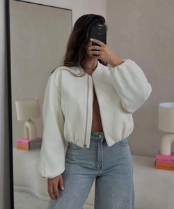 Detail of ivory bomber jacket with lantern sleeves and rhinestone straight jeans