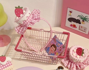 Pink checkered plush headband with 3D strawberry cake decor in a small storage basket